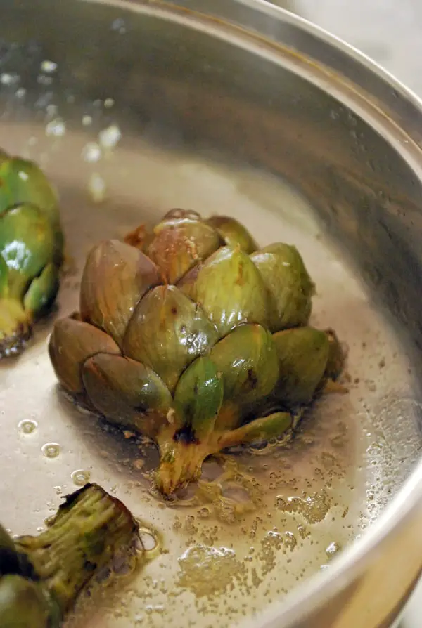 Estas alcachofas asadas son una exquisitez, la alcachofa se complementa de maravilla con un toque ácido del limón y la riqueza y profundidad del ajo con muy pocos ingredientes hacen una comida para chuparse los dedos literalmente.