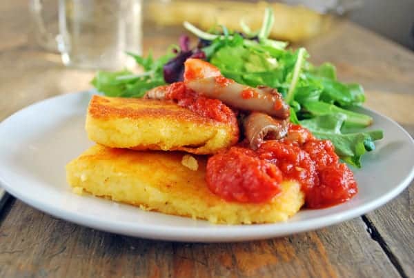 Polenta crujinete por fuera, suave por dentro con una espectacular salsa de jitomate y setas. La polenta es un plato de origen italiano que se hace a partir del maíz y es perfecta para cuando hace frío pero al hacerla de esta manera no importa si hace frío o calor siempre se me antoja. Para hacer este plato lo primero que hay que hacer es un caldo de verduras. En una cacerola sofreímos un poco de cebolla, pimiento, ajo, zanahoria y apio, en cuanto tomaron un poco de color llenamos la olla con agua y lo llevamos al hervor por lo menos por media hora. Este caldo será la base para cocinar la polenta y le dará un sabor único, si prefieren hacerlo con agua se puede sin problema y también será rica pero un buen caldo definitivamente le da mucha más profundidad de sabores al plato. Una vez que tienen el caldo deben cocinar la polenta (como diga la caja) poniendo poco a poco la polenta para que no se hagan grumos y revolviendo constantemente. Cuando esta lista la es momento sazonarla bien, agregarle una buena cantidad de queso parmesano y gouda, un poco de mantequilla y si quieren alguna hierba de olor. El resultado será una textura sedosa. Una vez lista en una bandeja previamente aceitada colocamos la polenta, la estiramos dejándola a un grosor de un centímetro más o menos y los dejamos enfriar por completo. Verán que al enfriarse se endurece y es entonces momento cortarla en porciones para dorarlas. Por otro lado, hay que hacer una salsa la cual puede ser una como la de esta pasta, o un ragú, pero esta vez hice una con setas la cual quedo de lujo con la polenta. Para eso cocine pimiento morrón, cebolla y ajo con un poco de mantequilla hasta que las verduras estaban suaves, le puse las setas y una vez que soltaron sus jugos les agregue el jitomate licuado. La cocine por unos 20 minutos, la saque del fuego y le puse bastantes hojas de albahaca fresca. Lo siguiente es armar el plato, para eso en una sartén bien caliente con un poco de aceite doramos los trozos de polenta por ambos lados, una vez crujientes los ponemos en un plato y por encima ponemos un poco de la salsa. Es una delicia que no se pueden perder.