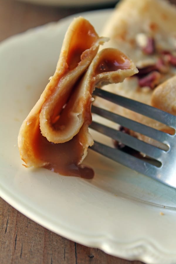 Un tendor pinchando un trozo de crepa rellenas de dulce.