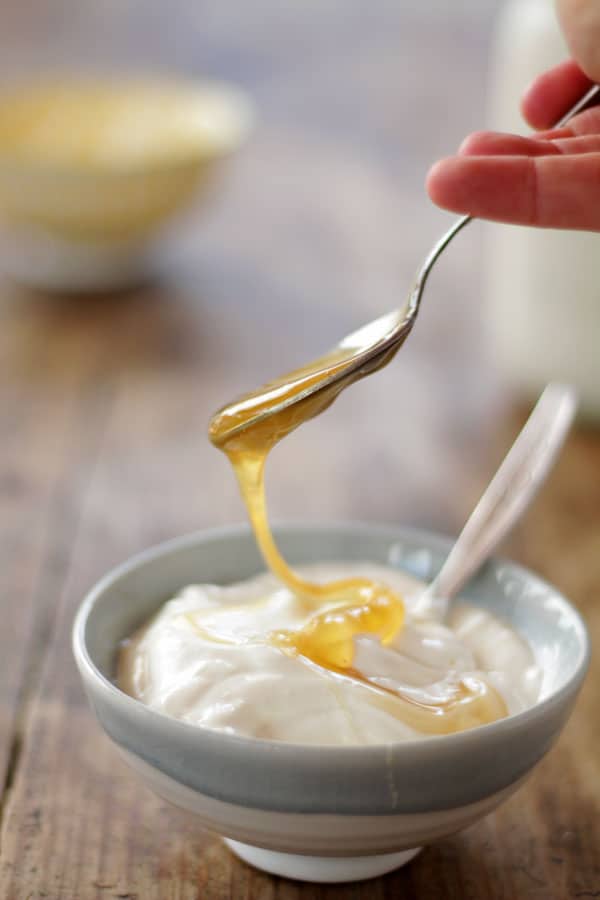 pouring honey on a plate of homemade yogurt