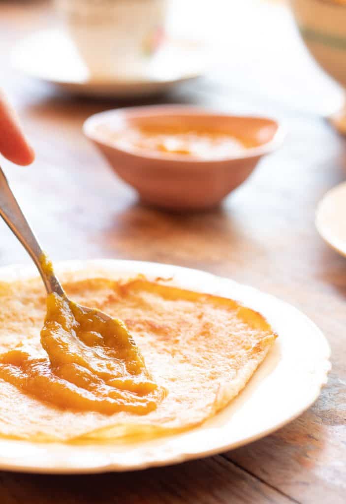 poniendo mermelada de mango sobre una crepa de avena