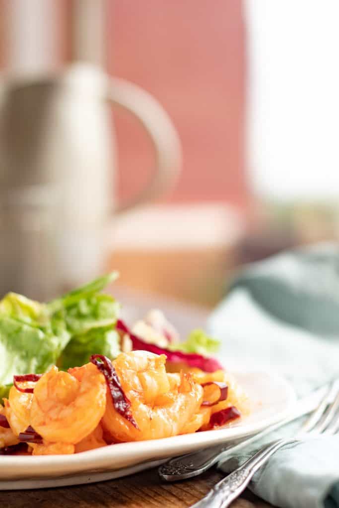 Camarones al ajillo servidos en un plato junto a una ensalada