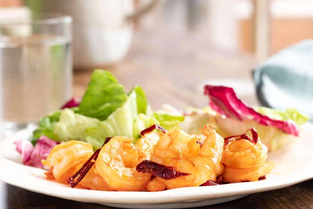 Camarones al ajillo servidos en un plato junto a una ensalada