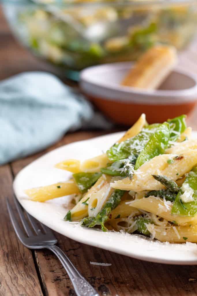 pasta primavera servida en un plato, con un tenedor a un lado.