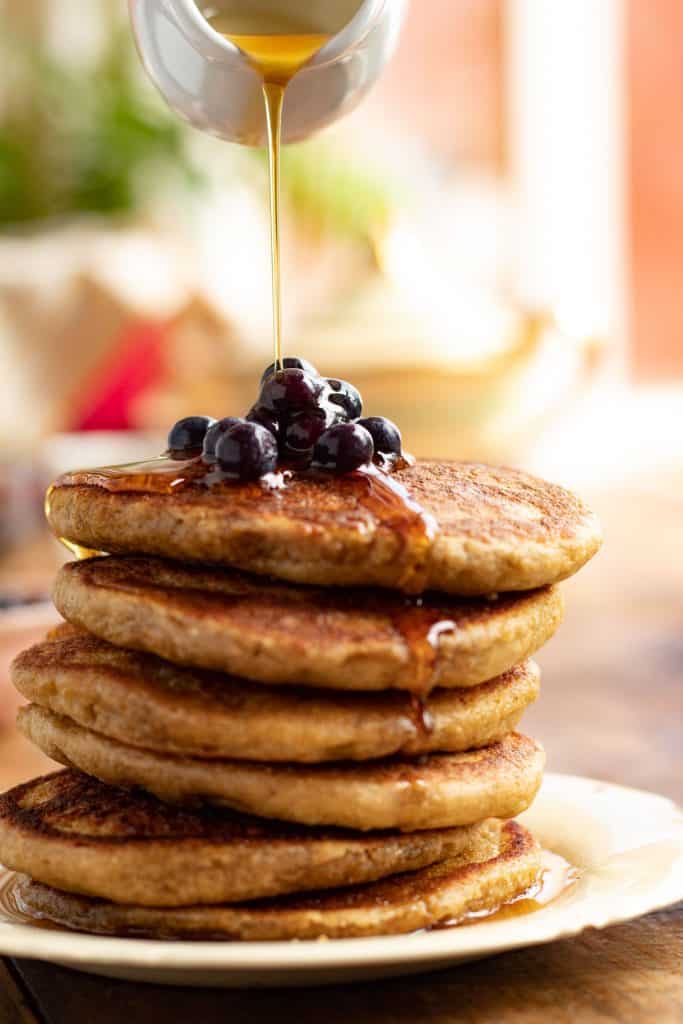 panqueques de avena servidos en un plato con bluberrys encima y miel de maple 