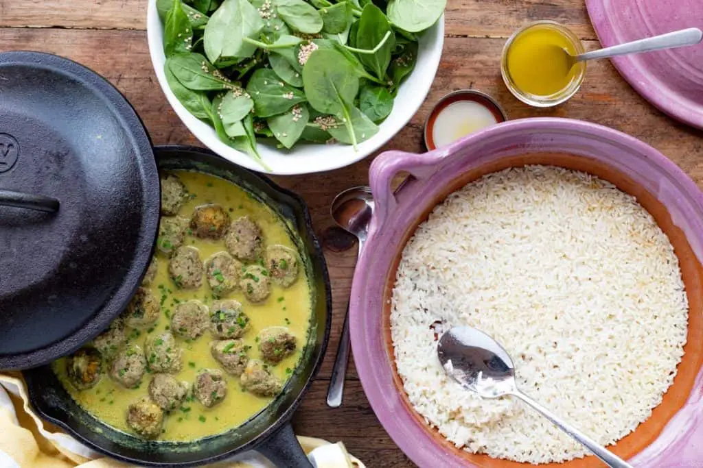 tres cacerolas una con albondigas, arroz y espinacas.