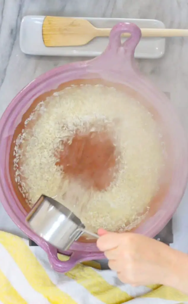 vertiendo agua en una caerola con arroz