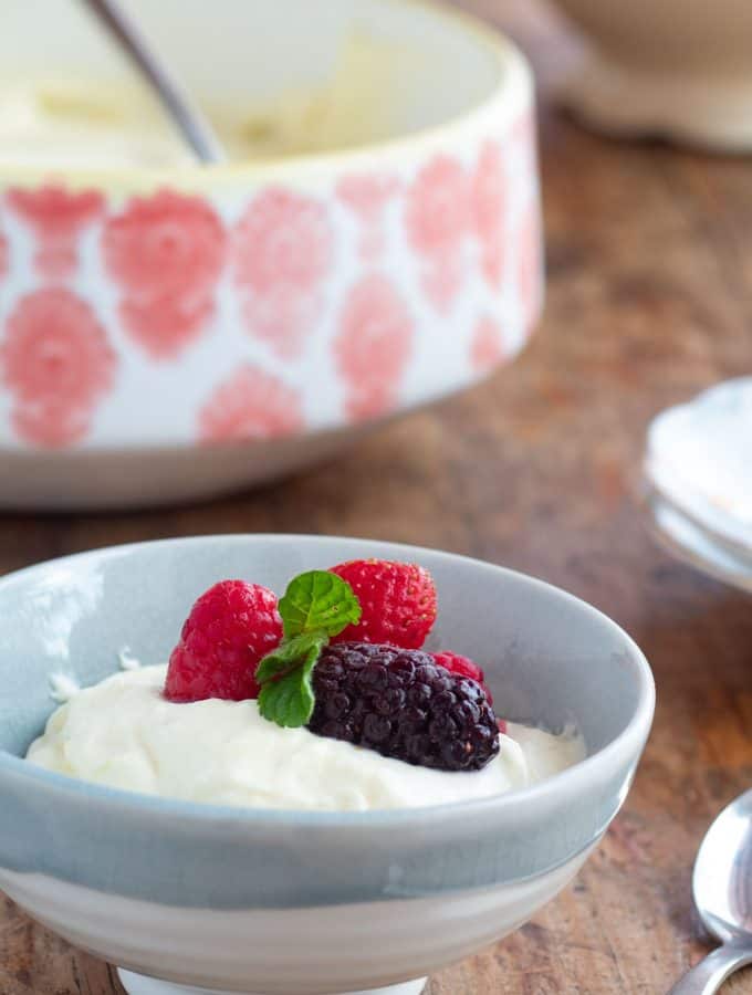 Mousse de limón servido en un plato con frutos rojos por encima y unas hojas de menta