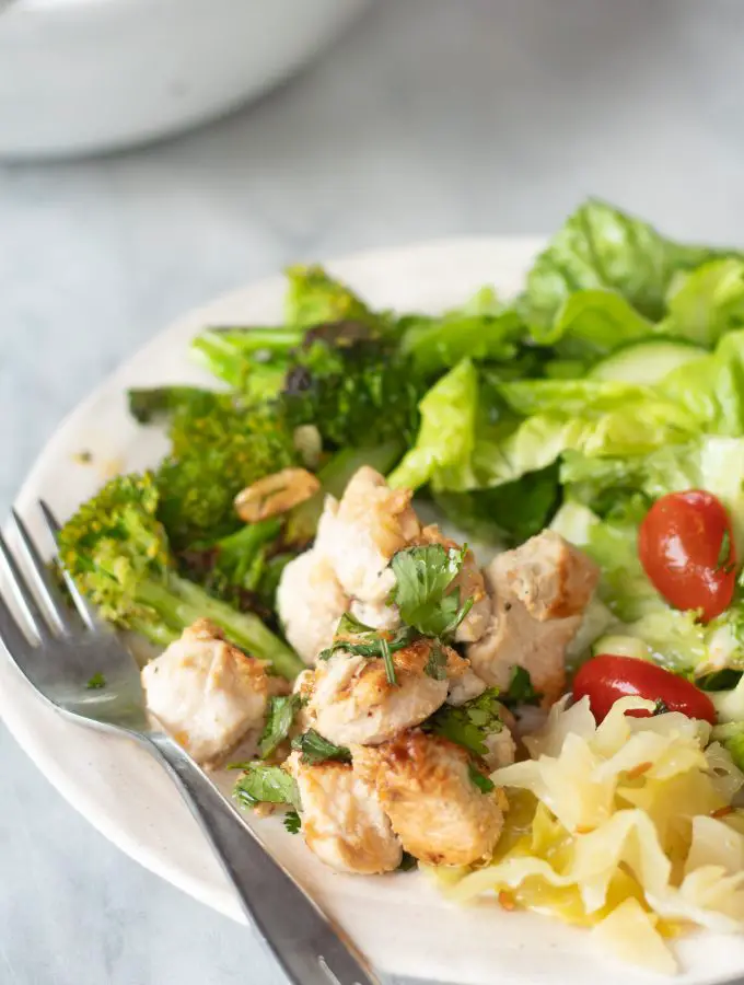 Plato con pechugas de pollo cortadas en cubos cocinadas y ensalada verde