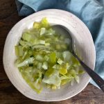 sopa de verduras servida en un plato hondo con una servilleta de tela a un lado.