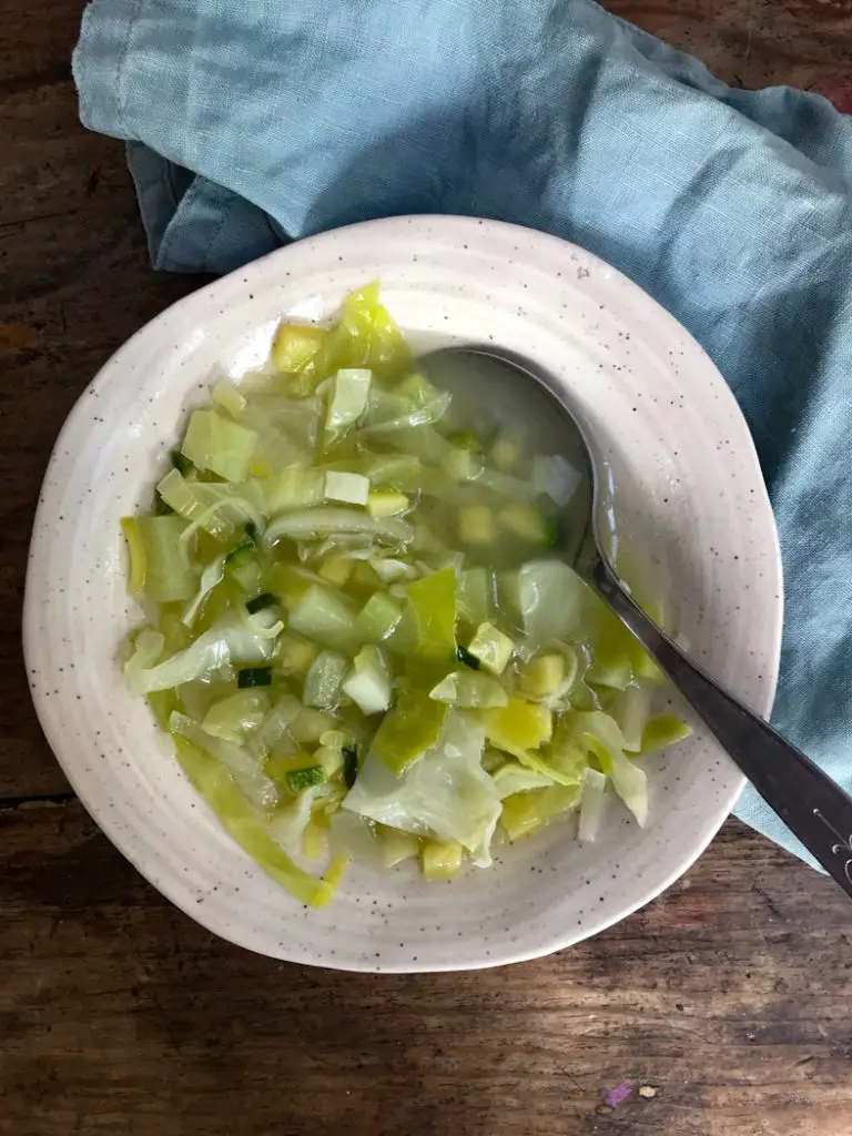 sopa de verduras servida en un plato hondo con una servilleta de tela a un lado.