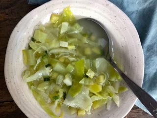 sopa de verduras servida en un plato hondo con una servilleta de tela a un lado.