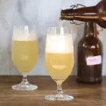 Botella sirviendo tepache en una copa