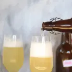 Botella sirviendo tepache en una copa